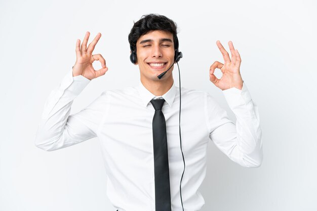 Telemarketer hombre trabajando con un auricular aislado sobre fondo blanco en pose zen