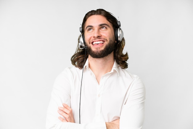 Telemarketer hombre trabajando con un auricular sobre fondo blanco aislado mirando hacia arriba mientras sonríe