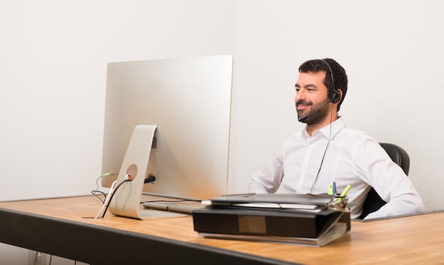 Telemarketer homem em um escritório posando com os braços no quadril e rindo olhando para a frente