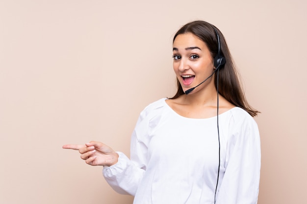 Telemarketer joven mujer sorprendida y apuntando con el dedo a un lado