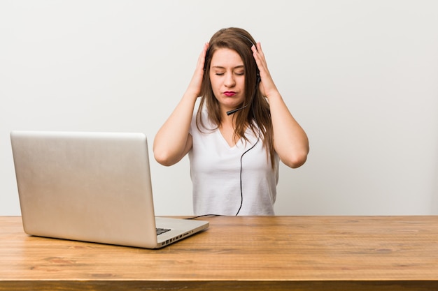 Telemarketer joven mujer tocar templos y tener dolor de cabeza.