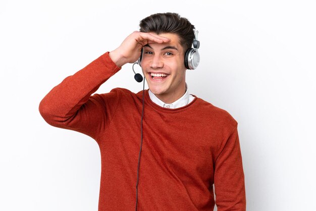 Telemarketer kaukasischer Mann, der mit einem Headset arbeitet, das auf weißem Hintergrund isoliert ist und mit der Hand weit weg schaut, um etwas zu sehen