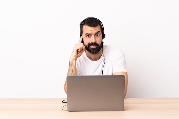 Telemarketer kaukasischer Mann, der mit einem Headset und mit Laptop arbeitet, der eine Idee denkt.