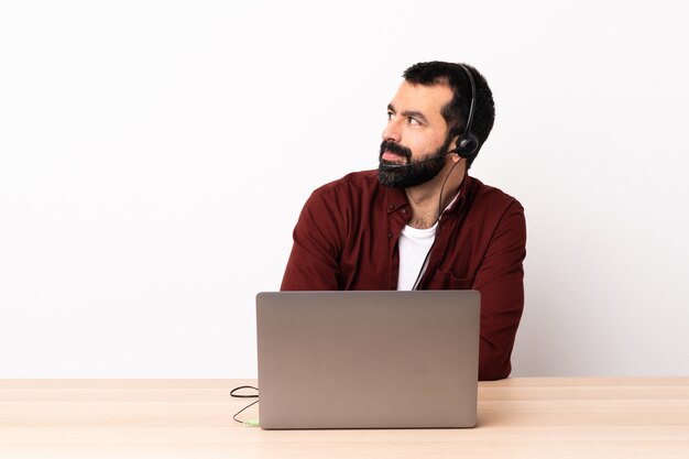 Telemarketer kaukasischer Mann, der mit einem Headset und mit Laptop arbeitet, der zur Seite schaut