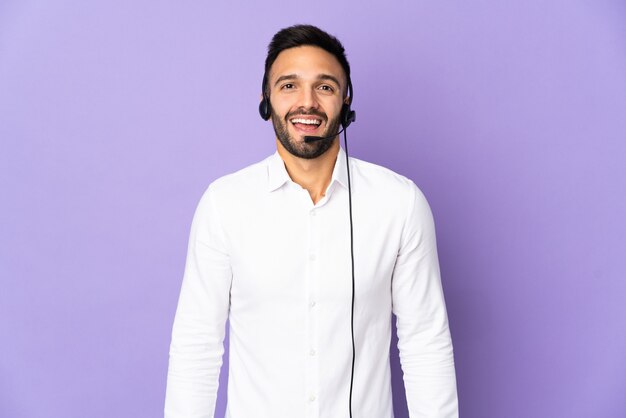 Telemarketer-Mann, der mit einem Headset arbeitet, das auf lila Wand mit überraschendem Gesichtsausdruck isoliert wird