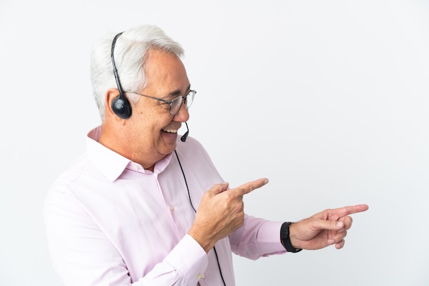 Telemarketer Mann mittleren Alters, der mit einem Headset arbeitet, das auf weißem Hintergrund isoliert ist, mit dem Finger zur Seite zeigt und ein Produkt präsentiert