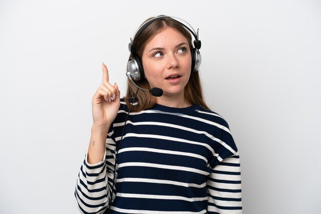 Telemarketer mujer caucásica que trabaja con un auricular aislado sobre fondo blanco con la intención de darse cuenta de la solución mientras levanta un dedo