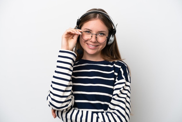 Telemarketer mujer caucásica trabajando con un auricular aislado sobre fondo blanco con gafas y feliz