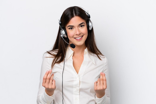 Telemarketer mujer caucásica trabajando con un auricular aislado sobre fondo blanco haciendo gesto de dinero