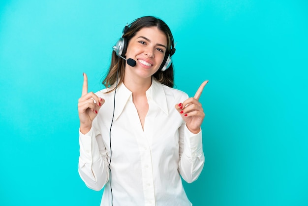 Telemarketer mujer italiana que trabaja con un auricular aislado sobre fondo azul apuntando a una gran idea