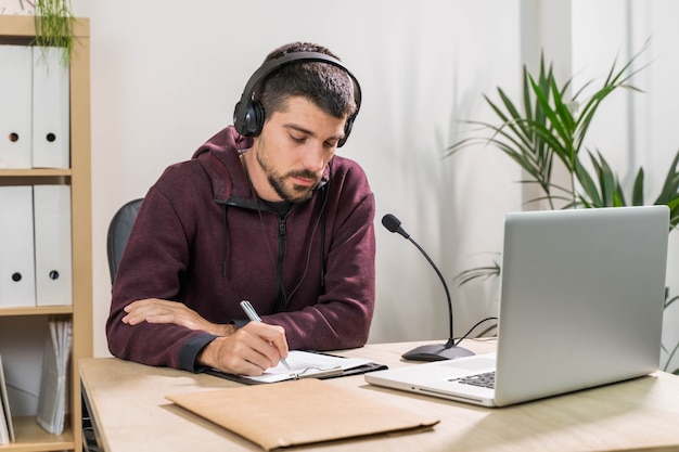 Telemarketer oder Podcast-Mann, der mit Laptop arbeitet und im Büro über ein Headset mit Gesichtsmaske spricht