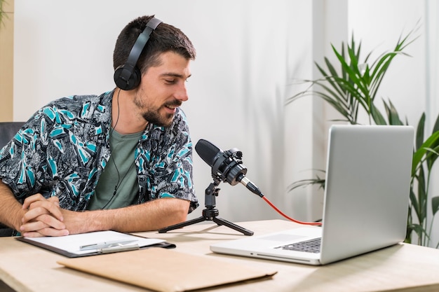 Telemarketer oder Podcast-Mann, der mit Laptop arbeitet und im Studiobüro über ein Headset spricht