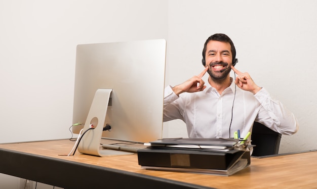 Telemarketermann in einem Büro lächelnd mit einem glücklichen und angenehmen Ausdruck