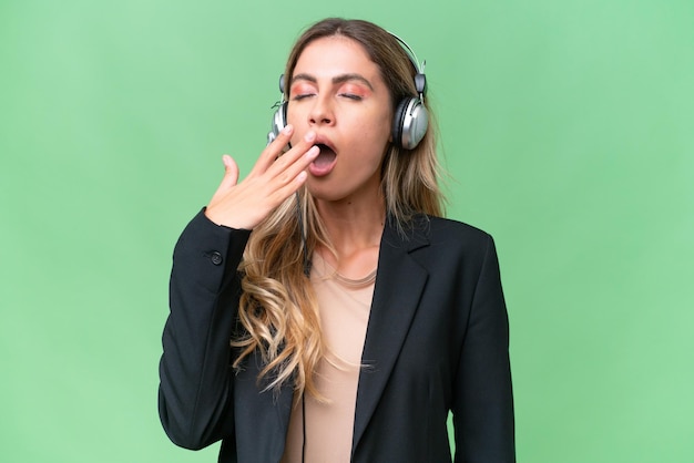 Telemarketing linda mulher uruguaia trabalhando com um fone de ouvido sobre fundo isolado bocejando e cobrindo a boca aberta com a mão