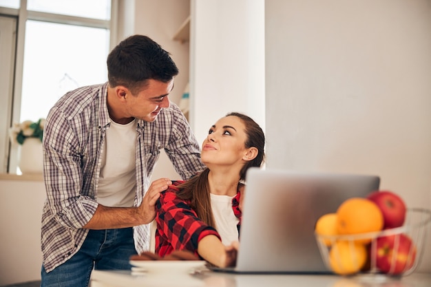 Teletrabajador femenino mirando a su guapo cónyuge masculino