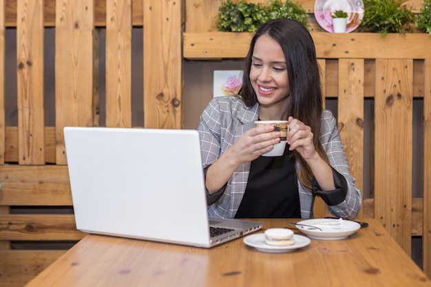 Teletrabalhador positivo tomando café e usando laptop