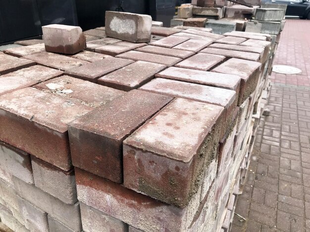 Telha de cimento vermelho de pedra de pavimentação para colocação de pavimento de construção de estradas em paletes de madeira em um canteiro de obras