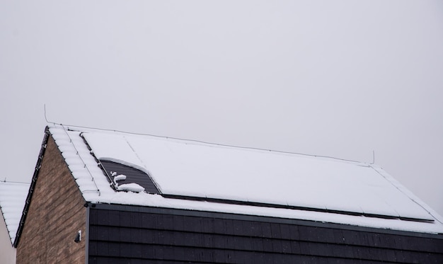 Foto telhado de uma casa com painéis solares cobertos de neve.