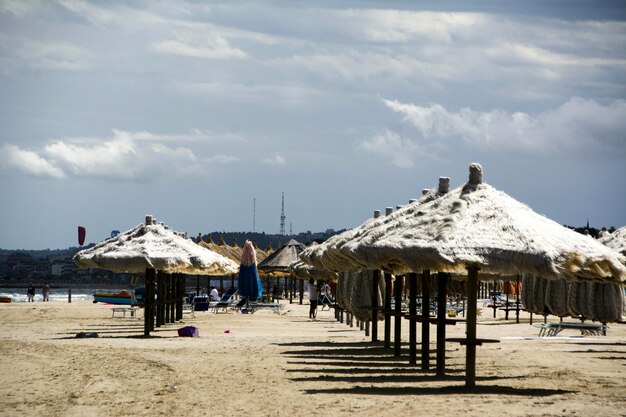 Telhados de palha na areia na praia contra o céu