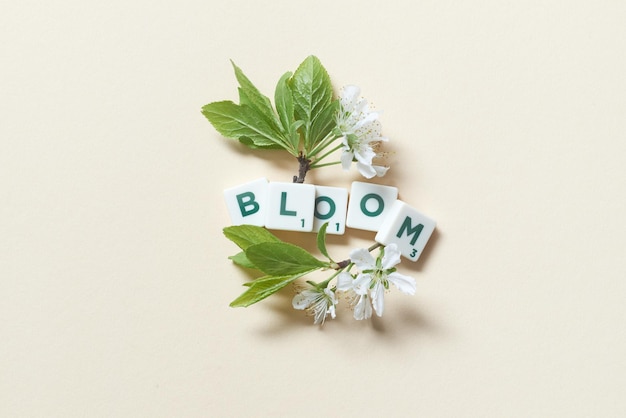 Telhas de Scrabble com flor de primavera em fundo bege