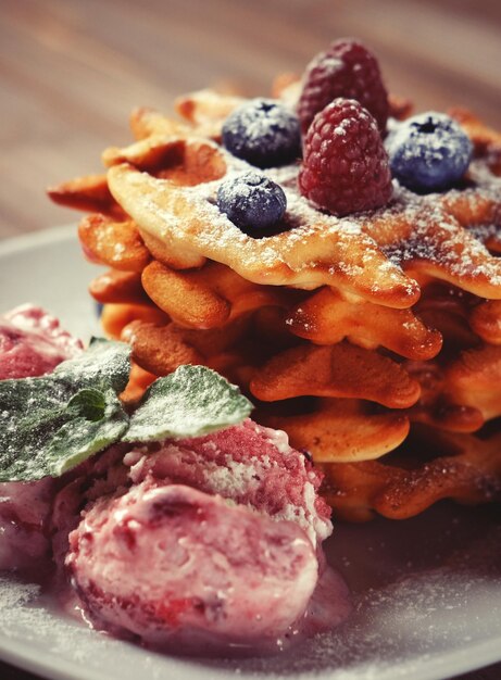 Teller mit belgischen Waffeln mit Eis und frischen Beeren, Himbeeren und Blaubeeren