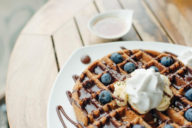 Teller mit belgischen Waffeln mit Eiscreme-Schokoladensauce und frischen Blaubeeren