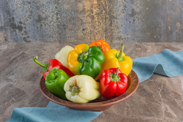 Teller mit bunten frischen Paprika auf Marmoroberfläche