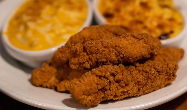 Teller mit Chicken Fingers mit Beilage von Makkaroni und Käse.