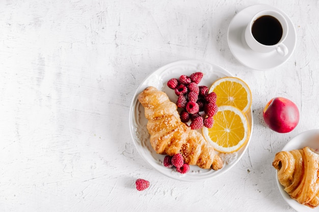 Teller mit Croissant und Früchten