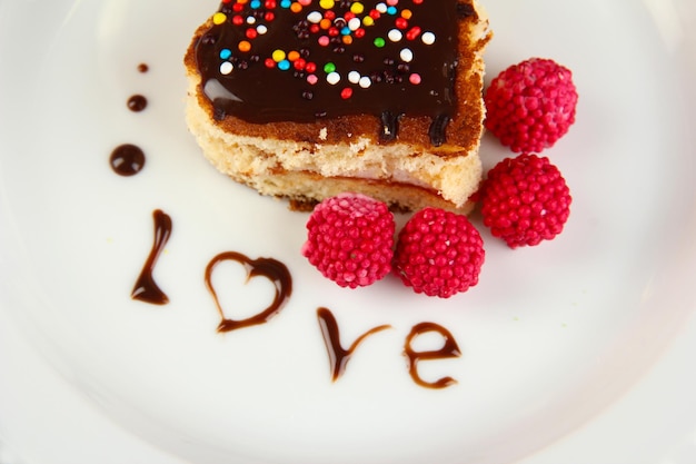 Teller mit Dessert in Herzform auf festlichem Tisch zu Ehren des Valentinstags aus nächster Nähe