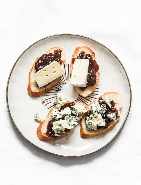 Teller mit Feigenmarmelade Gorgonzola und Brie-Käse-Bruschetta auf hellem Hintergrund Draufsicht