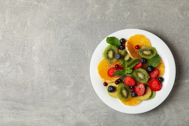 Teller mit frischem Obstsalat auf grau