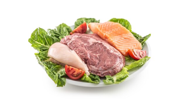 Teller mit frischem Rindfleisch, Hühnchen und Lachs auf Salatblättern, mit isoliertem weißem Hintergrund.