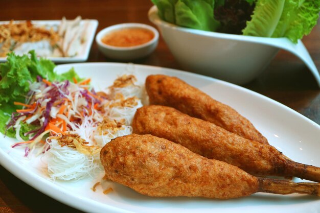 Teller mit frittierten vietnamesischen gehackten Garnelen, die um Zuckerrohr gewickelt sind, mit Reisfadennudeln