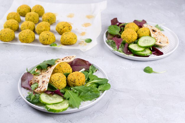 Teller mit gebackener Falafel mit Fladenbrot, Sauce und Salatblättern