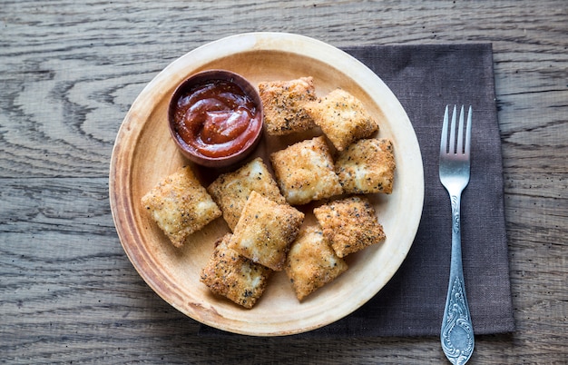 Teller mit gebratenen Ravioli auf dem Holzbrett