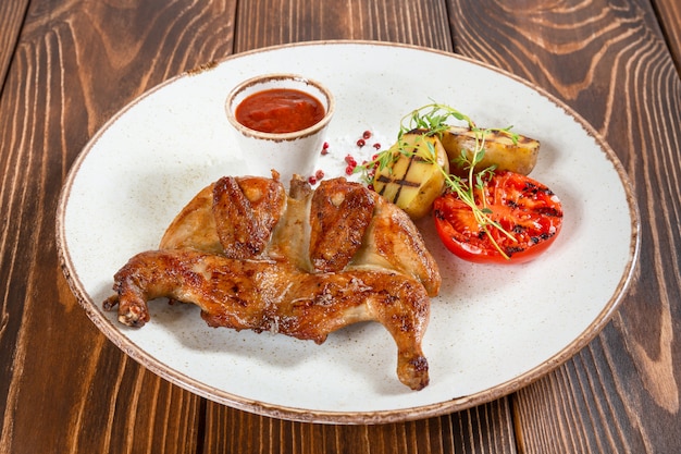 Foto teller mit gegrilltem hähnchen und gemüse mit tomatensauce auf holztisch