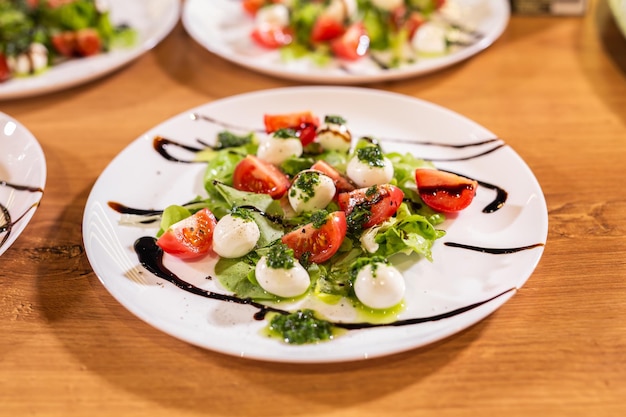 Teller mit gesundem, klassischem Caprese-Salat aus der Nähe mit Mozzarella-Käsetomaten und Basilikum in der italienischen Küche
