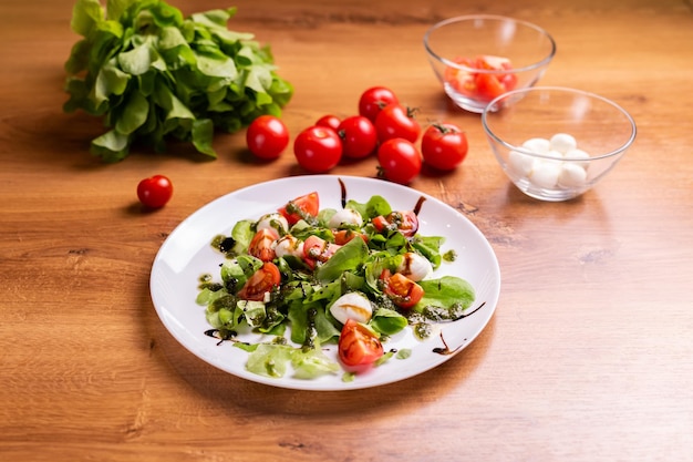 Teller mit gesundem, klassischem Caprese-Salat aus der Nähe mit Mozzarella-Käsetomaten und Basilikum in der italienischen Küche