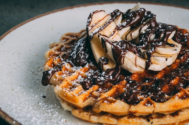 Foto teller mit gourmet-waffeln mit schokoladen- und bananenscheiben