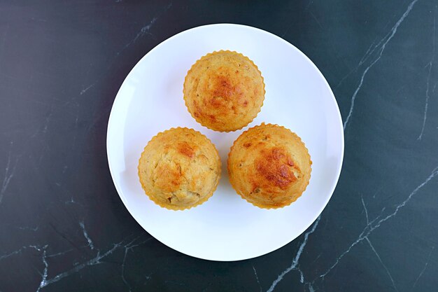 Teller mit hausgemachten Bananen-Muffins auf dem Tisch aus schwarzem Marmor