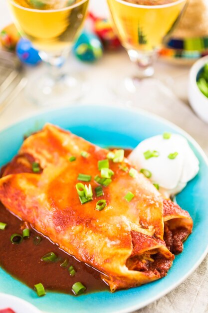 Teller mit Hühnchen-Enchiladas, garniert mit Frühlingszwiebeln und Sauerrahm.