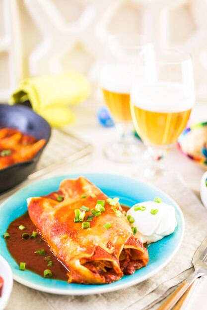 Teller mit Hühnchen-Enchiladas, garniert mit Frühlingszwiebeln und Sauerrahm.