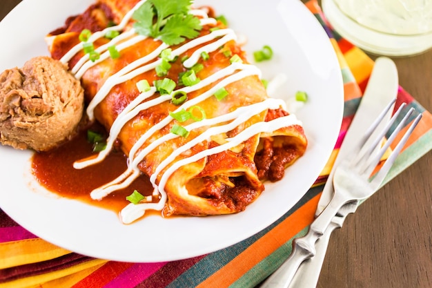 Teller mit Hühnchen-Enchiladas, garniert mit Frühlingszwiebeln und Sauerrahm.