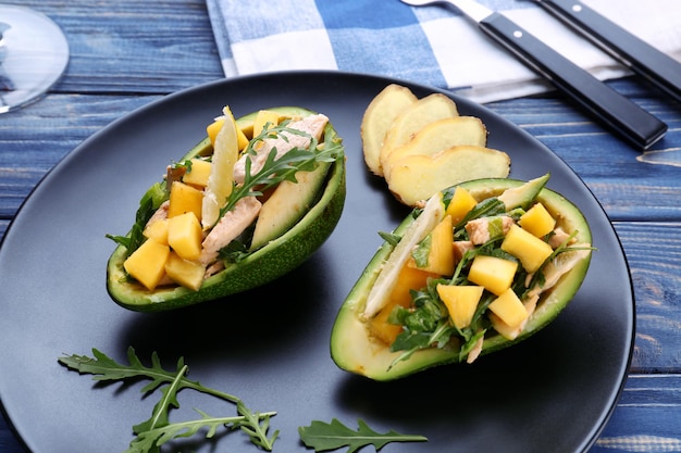 Teller mit Hühnchensalat in Booten aus Avocado auf dem Tisch