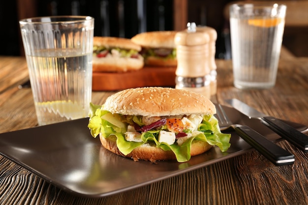 Teller mit Hühnersalat im Burgerbrötchen auf dem Tisch