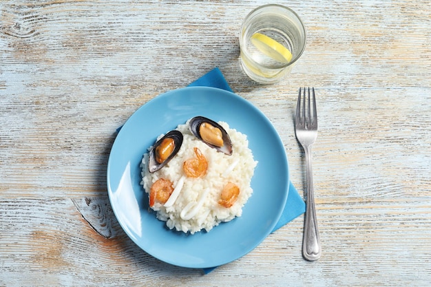 Teller mit leckerem Risotto mit Meeresfrüchten auf Holzhintergrund