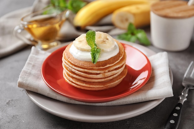 Teller mit leckeren Bananenpfannkuchen auf Küchentisch