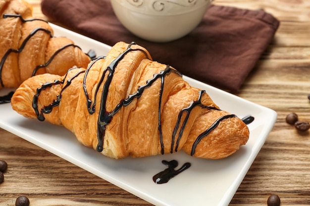 Teller mit leckeren Croissants auf Holztisch in der Nähe