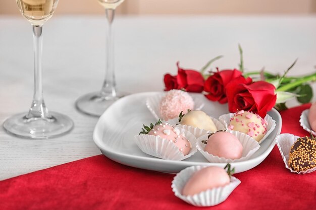 Teller mit leckeren glasierten Erdbeeren auf dem Tisch